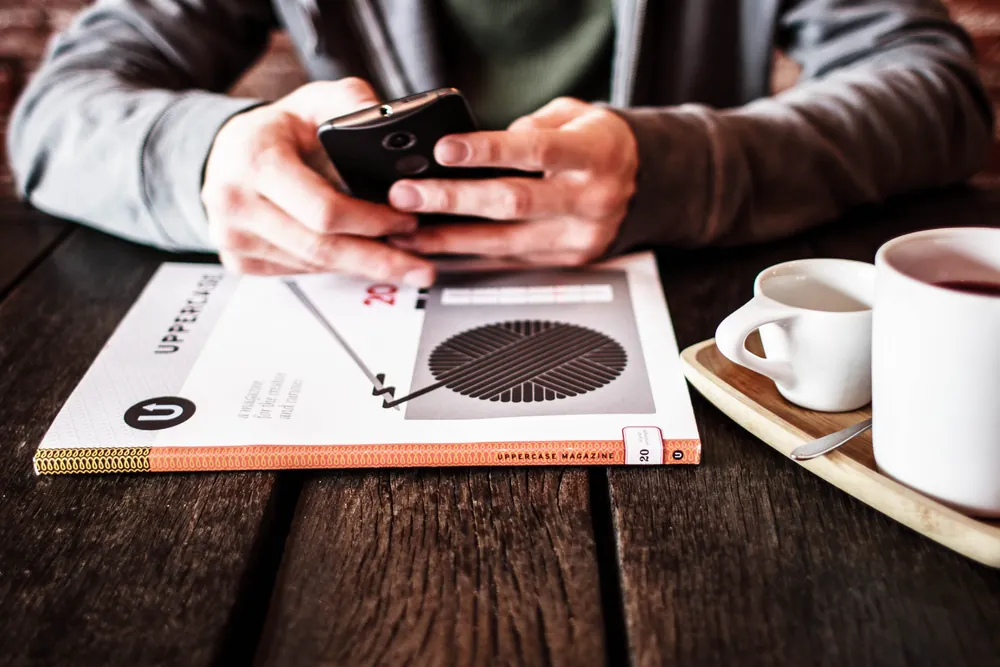 カフェのテーブルでスマートフォンを操作する人